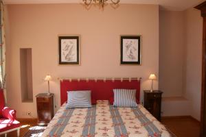 una camera con un letto con un testata rossa e due lampade di Château de La Grèze a Beaulieu-sur-Dordogne