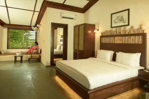 una camera con un letto e una donna seduta su una sedia di Asiatic Lion Lodge a Sasan Gir Altre 37 foto