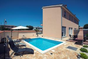 a swimming pool with two chairs and a building at Villa Lara 1 in Ližnjan