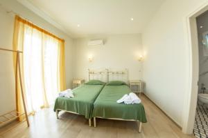 a bedroom with a green bed with towels on it at Taxi Driver Apartments in Paleokastritsa
