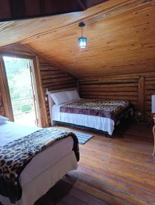 a bedroom with two beds in a log cabin at Pousada Recanto da Pantera in Cunha
