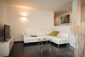 a living room with a white couch and a tv at Apartment Villa Laurin in Pianizza di Sotto