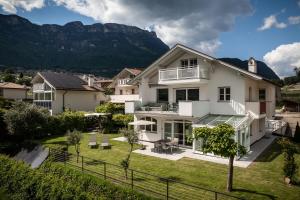 a white house with mountains in the background at Apartment Villa Laurin in Pianizza di Sotto
