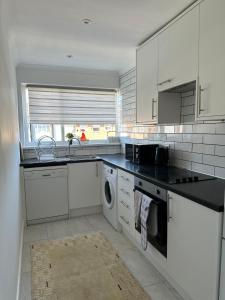 a kitchen with white cabinets and a black counter top at Stylish 2 Bedroom Flat Slough in Slough