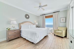 una camera da letto bianca con un letto e una sedia di Indigo Unit 1406e a Pensacola