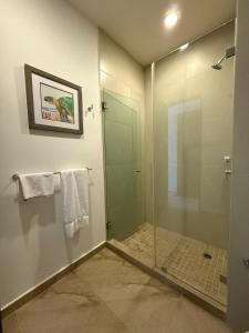 a bathroom with a shower with a glass door at Selva Tulum - HiveNB in Tulum