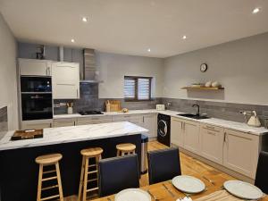 a large kitchen with a counter and stools in it at Lakefront Lodge with Hot Tub - Aylesbury Lodge in Shepton Mallet