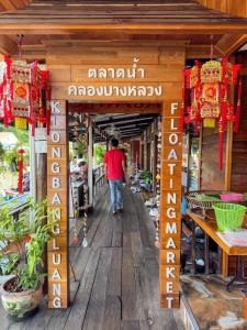 Ein Mann geht einen Holzsteg entlang in ein Geschäft in der Unterkunft Apartment Near Big Buddha in Bangkok Yai + 2 Fotos