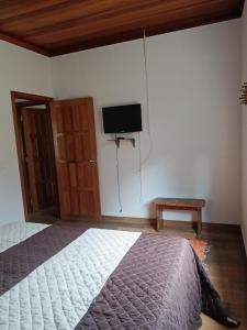 a bedroom with a bed and a tv on the wall at Pousada Recanto da Pantera in Cunha