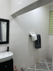 a white bathroom with a sink and a mirror at Da palm Inn in Aburi +21 photos