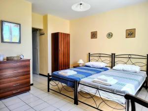 a bedroom with a bed and a wooden dresser at Cycladic Horizon Island Villa By Hostandros in Batsi
