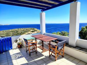 a table and chairs on a balcony with the ocean at Cycladic Horizon Island Villa By Hostandros in Batsi