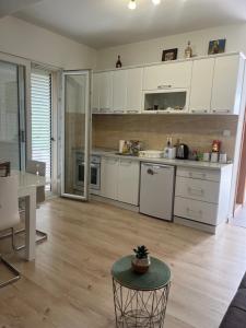 a kitchen with white cabinets and a table in a room at Apartman Iskra in Bijela +12 photos