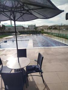 a table with an umbrella next to a swimming pool at Charmoso AP VOG VILLE Caruaru in Caruaru
