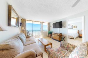 a living room with a couch and a television and a bed at Gulf House 202 in Gulf Shores