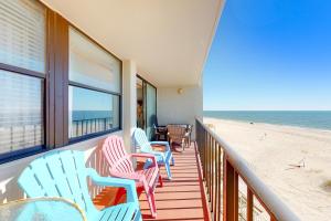 a balcony with blue and pink chairs and the beach at Gulf House 202 in Gulf Shores