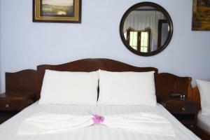 ダルダにあるTaverna Hotel Iliri - Dardheのベッドルーム1室(紫色の弓が付いたベッド1台付)