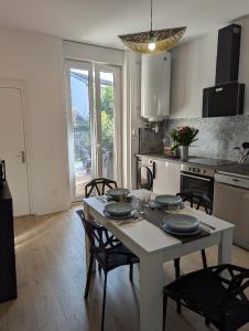 a kitchen with a white table and chairs and a table at Le petit cocon de Montrond in Montrond-les-Bains