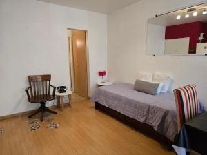 a bedroom with a bed and a chair and a cabinet at Luz Urbana BA Studio in Buenos Aires