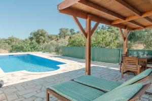 a patio with a table and chairs and a swimming pool at Casa da Serra - Moradia T2 in Montes Novos +8 photos