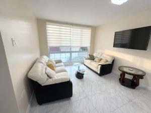 een woonkamer met twee banken en een flatscreen-tv bij Seacastle Beach Penthouse in Montego Bay