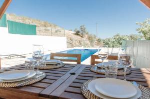 a wooden table with plates and wine glasses on it at Casa da Serra - Moradia T2 in Montes Novos