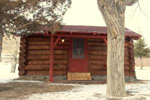 a log cabin with a red door and a tree at Family Cabin Rental on Beautiful Ranch near Yellowstone National Park, Wyoming in Wapiti +15 photos