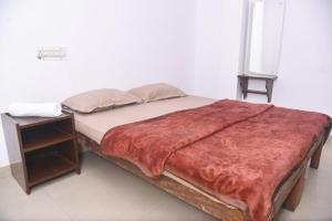 a bed with a red blanket and a night stand at Sai Comforts in Jāmb