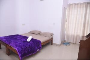 a bedroom with a bed with purple sheets and a window at Sai Comforts in Jāmb