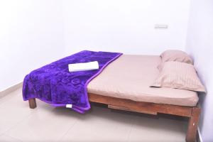 a small bed with a purple blanket on it at Sai Comforts in Jāmb