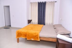 a bedroom with a bed with an orange blanket on it at Sai Comforts in Jāmb