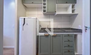 a kitchen with a white refrigerator and gray cabinets at Studio aconchegante- Japão liberdade in Sao Paulo