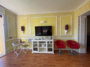 a living room with two red chairs and a television at Alloggio turistico fronte mare con vista da sogno in Ladispoli
