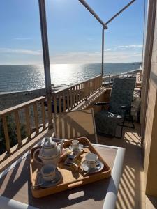 a table with a tea set on a balcony with the ocean at Alloggio turistico fronte mare con vista da sogno in Ladispoli