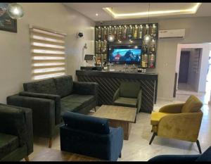 a living room with couches and a bar with a tv at La VOD Hotel in Benin City