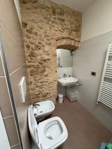 a bathroom with a stone wall and a toilet and sink at Vicolo Elegante in Ortona +11 photos