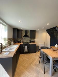 a kitchen with black cabinets and a table and a counter at Evergreen Cottage in East Preston