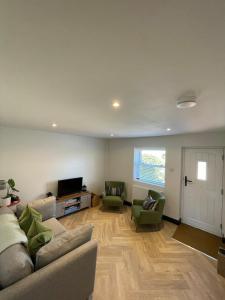 a living room with a couch and chairs and a tv at Evergreen Cottage in East Preston