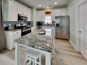 a kitchen with white cabinets and a marble counter top at Otter Oasis in Surf City