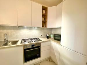 a kitchen with white cabinets and a stove top oven at Luxury apartment Erica sea view with common swimming pool just 10 mt from the beach in Golfo Aranci