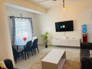 a living room with a table and a tv on the wall at Giannas stays 2br in Mombasa +12 photos