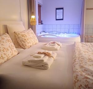 two towels on a bed with a bath tub at L'instant Beaujolais 2 ou 4 personnes Logis cosy balnéo vue jardin in Theizé
