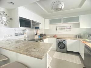 a kitchen with white cabinets and a washer and dryer at Modern & Spacious 2BR- Ville Haute Kenitra-Garage in Kenitra