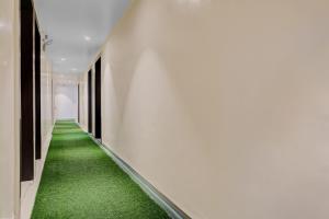 a corridor with green carpet in a building at Hotel O Parinda Lodging in Chinchwad