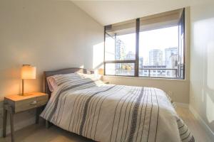 a bedroom with a bed with a large window at Beautiful Downtown Unit in Vancouver