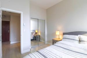 a white bedroom with a bed and a mirror at Beautiful Downtown Unit in Vancouver +5 photos