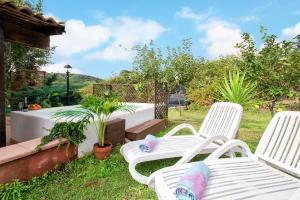 dwa białe krzesła siedzące na trawie na dziedzińcu w obiekcie Laurus Jacuzzi villa Alghero Valverde 122 w mieście Valverde