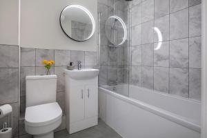 a bathroom with a toilet and a tub and a mirror at Stunning 1 Bedroom Apartment in a Converted Chapel - Free Parking, Smart TV, Fast WiFi and Self-Check-In by Yoko Property in St Asaph