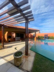 a patio with a pool and a wooden pergola at Duplex à 800 mts do Beach Park COM 5 suítes in Aquiraz