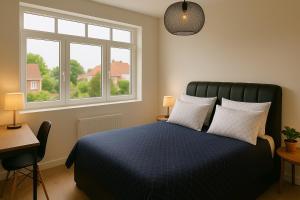 a bedroom with a blue bed with two windows at La Demeure Marcquoise in Marcq-en-Baroeul